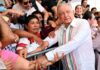 Los hijos de los personajes históricos Andrés Manuel López Obrador estrecha las manos de ciudadanos que lo rodean durante un acto público, mientras varias personas toman fotografías y observan de cerca su paso.