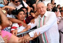 Los hijos de los personajes históricos Andrés Manuel López Obrador estrecha las manos de ciudadanos que lo rodean durante un acto público, mientras varias personas toman fotografías y observan de cerca su paso.