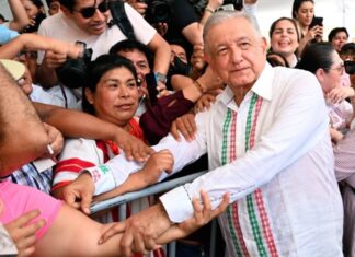 Los hijos de los personajes históricos Andrés Manuel López Obrador estrecha las manos de ciudadanos que lo rodean durante un acto público, mientras varias personas toman fotografías y observan de cerca su paso.