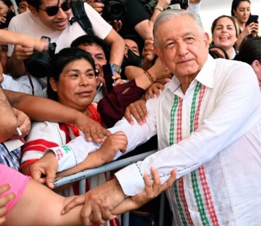 Los hijos de los personajes históricos Andrés Manuel López Obrador estrecha las manos de ciudadanos que lo rodean durante un acto público, mientras varias personas toman fotografías y observan de cerca su paso.